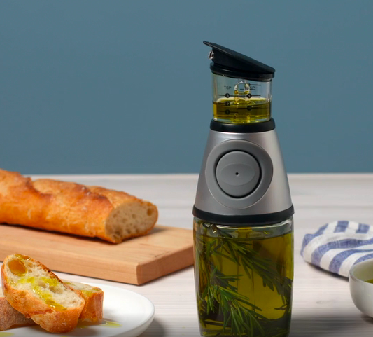 Glass olive oil bottle with rosemary inside base and measurement markers by the pouring cap 