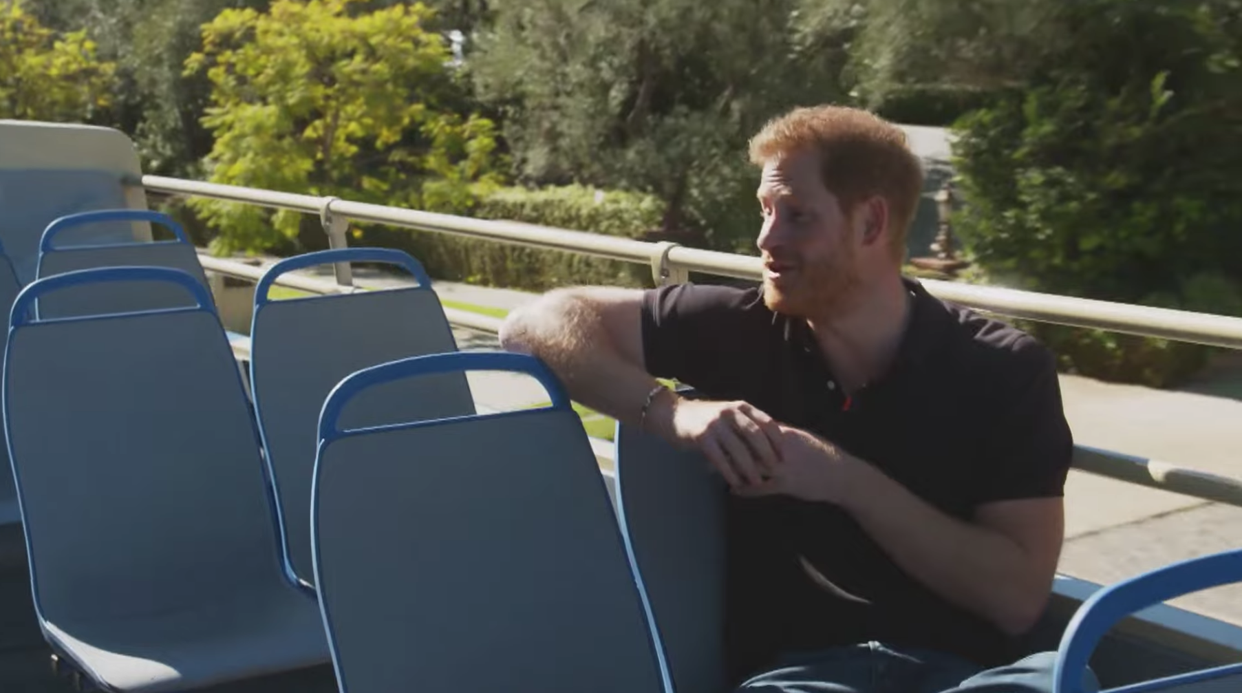 Prince Harry sitting on top of a sightseeing bus