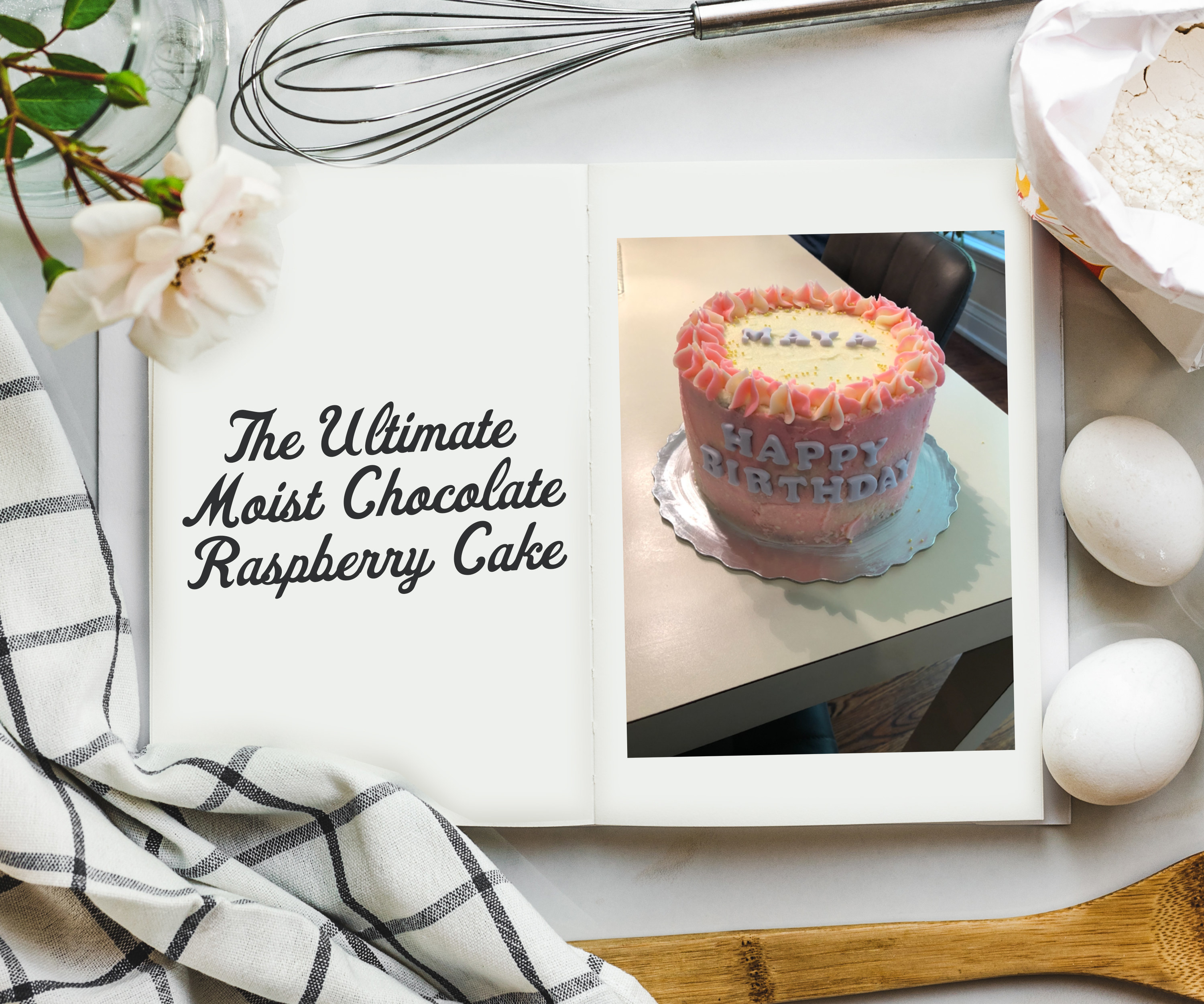 An overhead shot of cookbook on a table surrounded by ingredients and a photo on the inside of a multi-tiered cake that says Happy Birthday on the side. It&#x27;s covered in pink and white frosting.