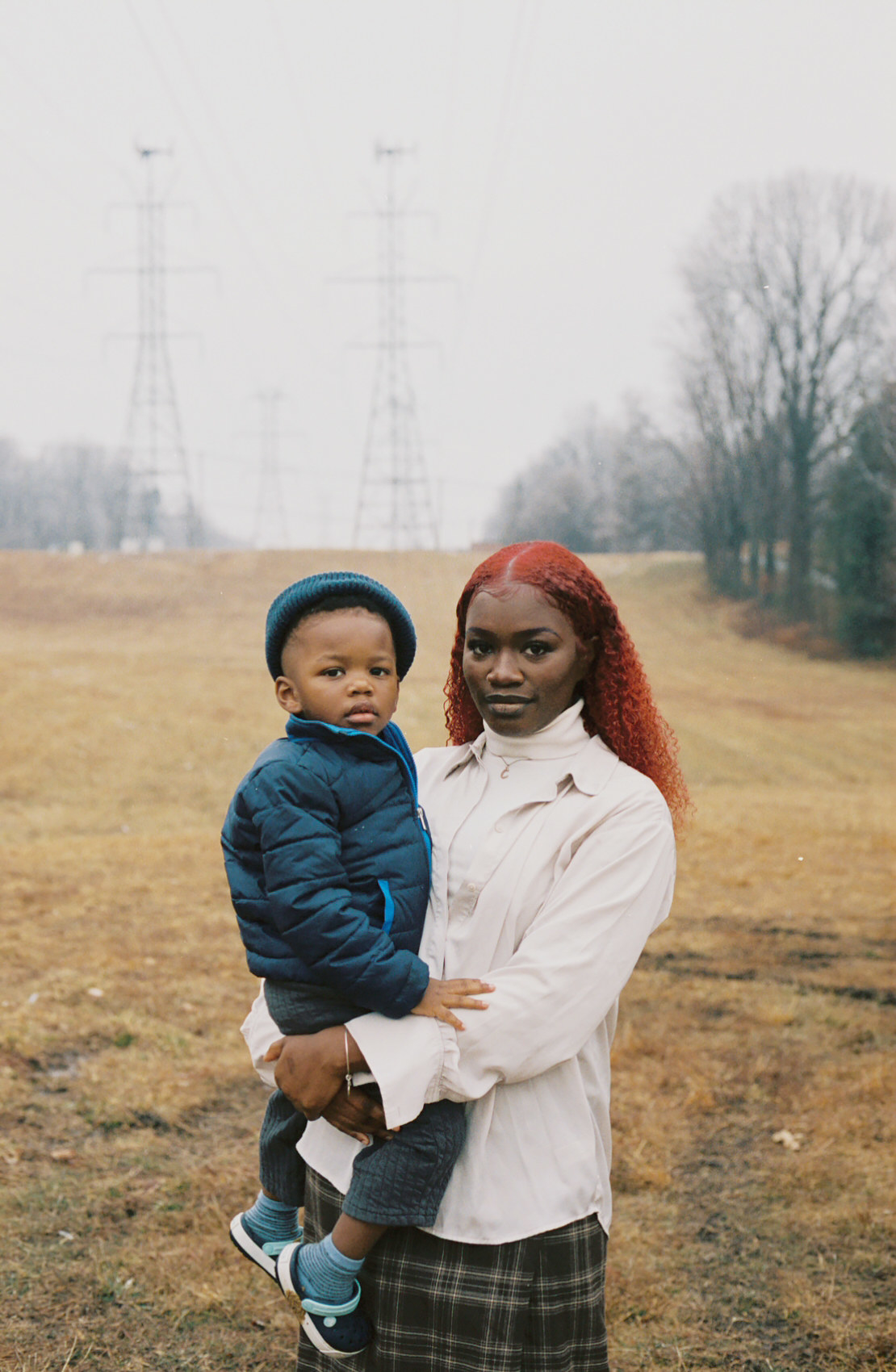 A woman holding a toddler standing in a field