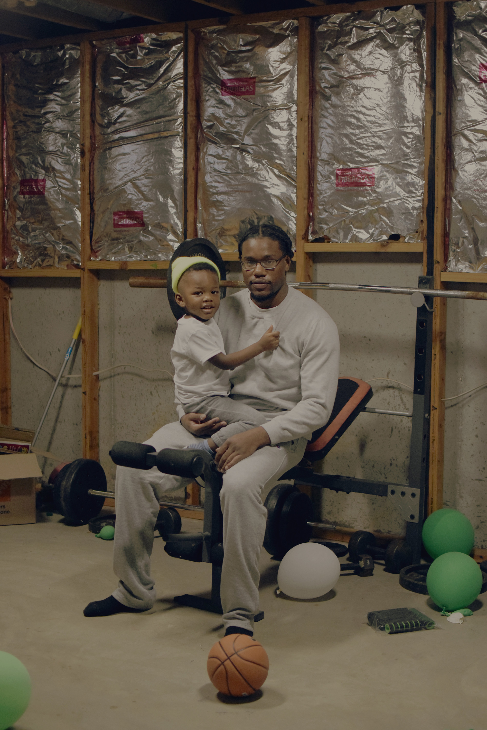 A man in a home gym holding a toddler