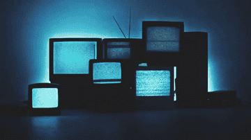 A pile of old televisions with static on their screens, ominously glowing