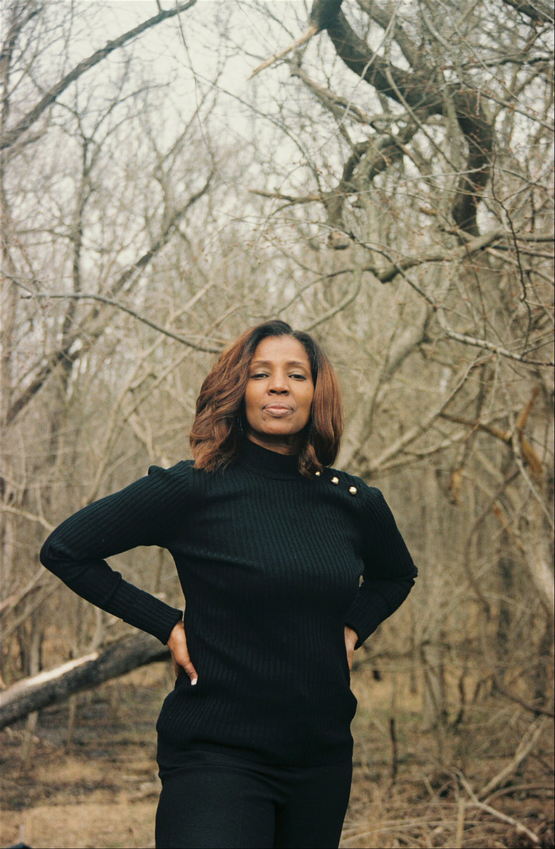 A middle-aged woman with woods behind her looking at the camera