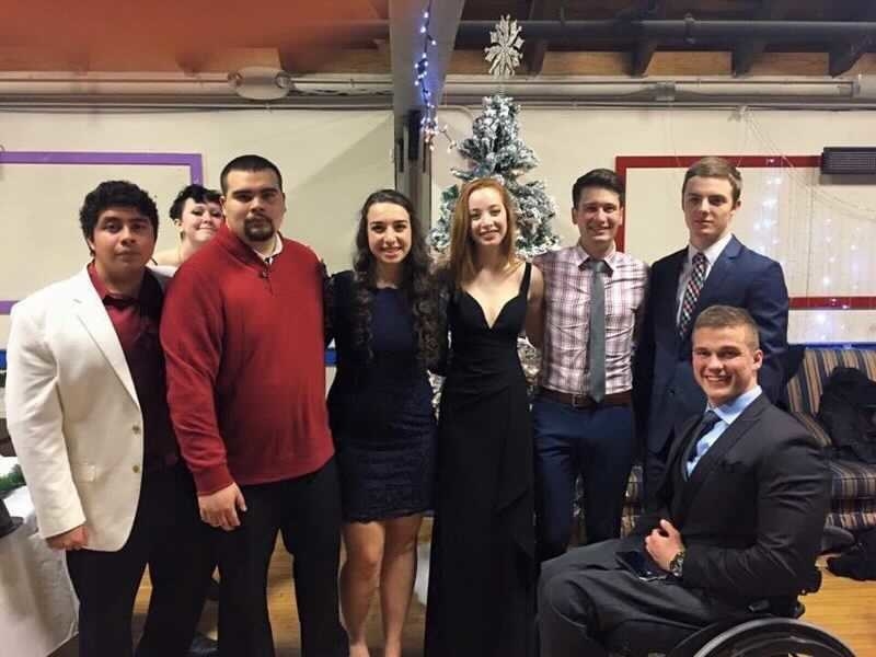 Eight people line up and pose in front of a Christmas tree