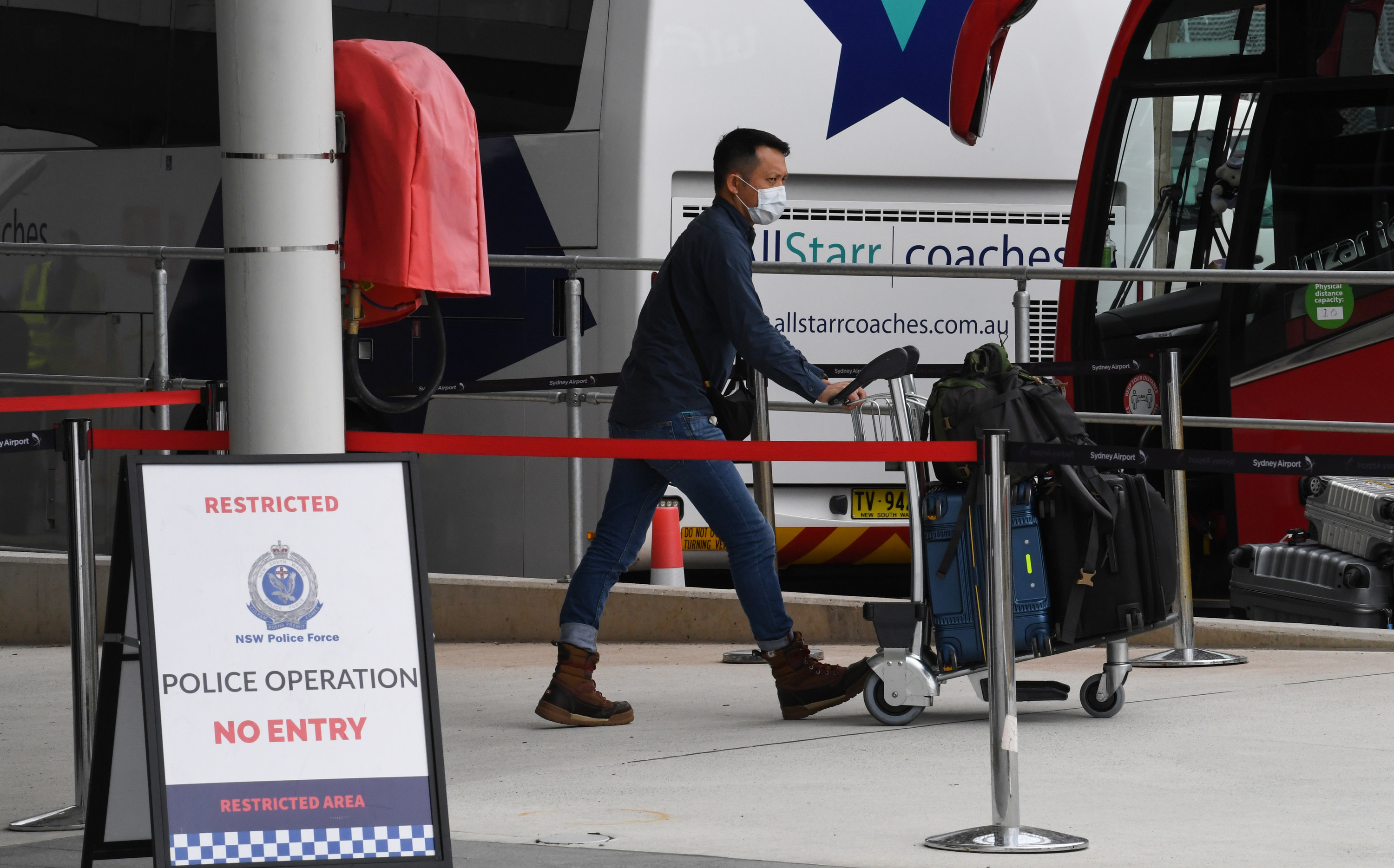 a passenger pushes luggage toward a bus