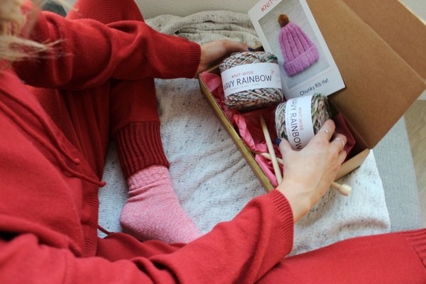 a model wearing pajamas and sitting next to the box filled with yarn