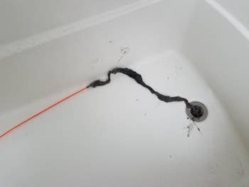 A review image of black goop and hair removed from the drain, in a tub