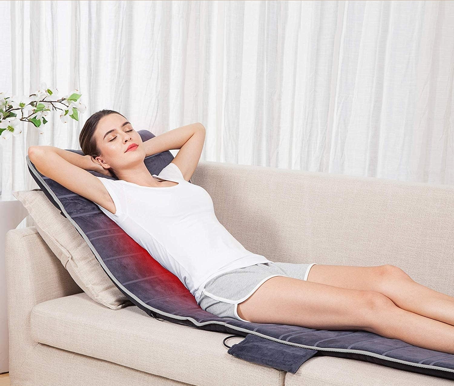 person lying on the couch with the massager mat under them