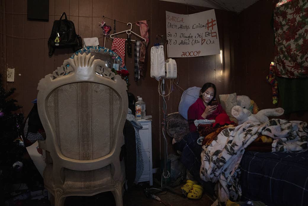 Nohemí&#x27;s daughter sits on the bed, connected to the machine that enables her to get food into her body