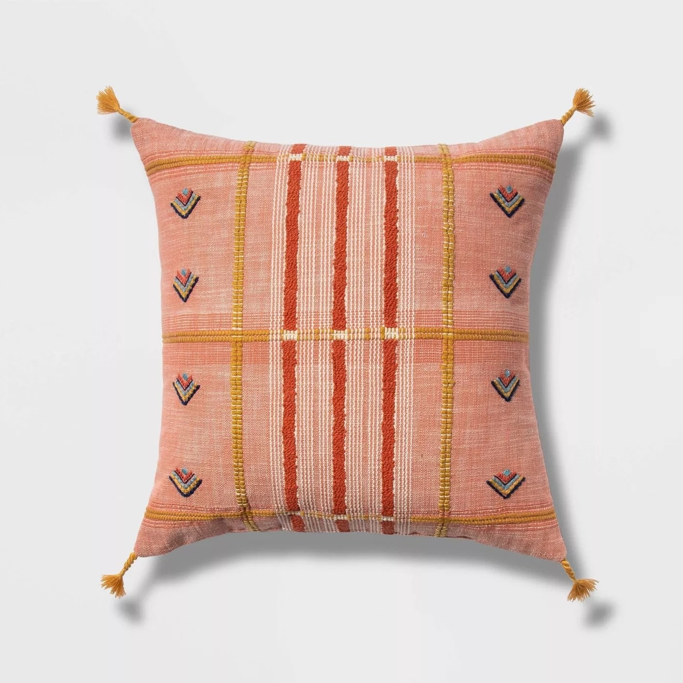 Square pillow with tassels on each corner and geometric patterns throughout