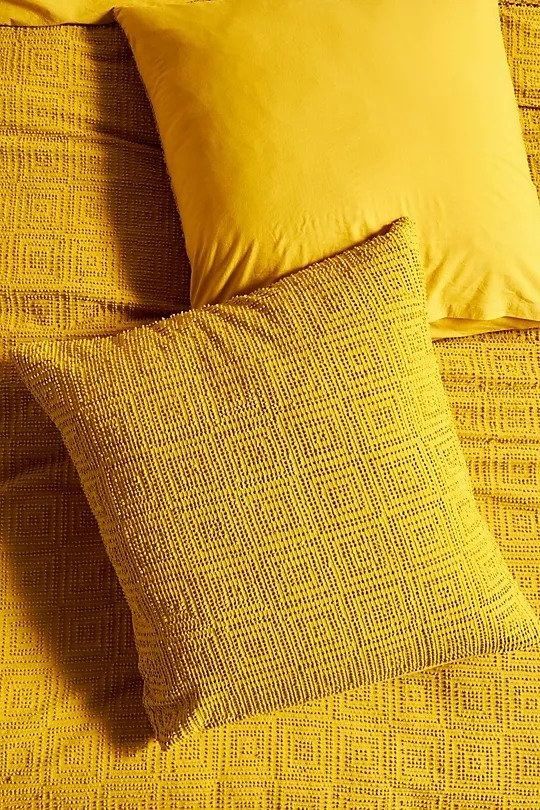 Bright yellow square throw pillow with rows of squares within squares as a pattern 