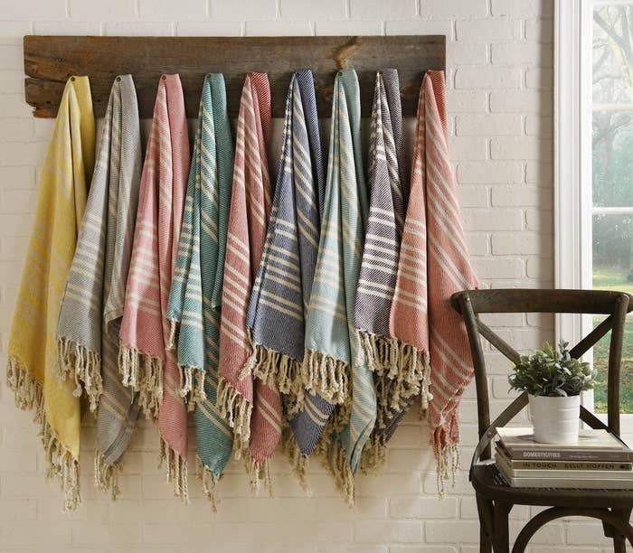 Several tasseled blankets hung up on a coat rack 
