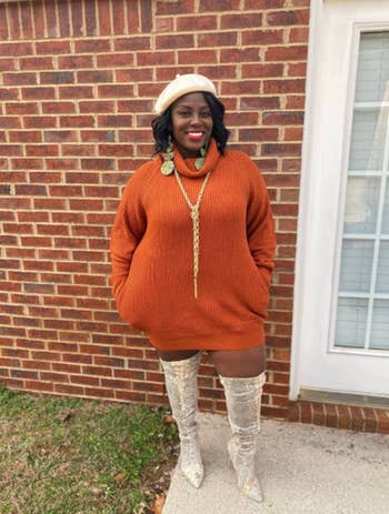 reviewer wearing orange dress with accent necklace and OTK boots