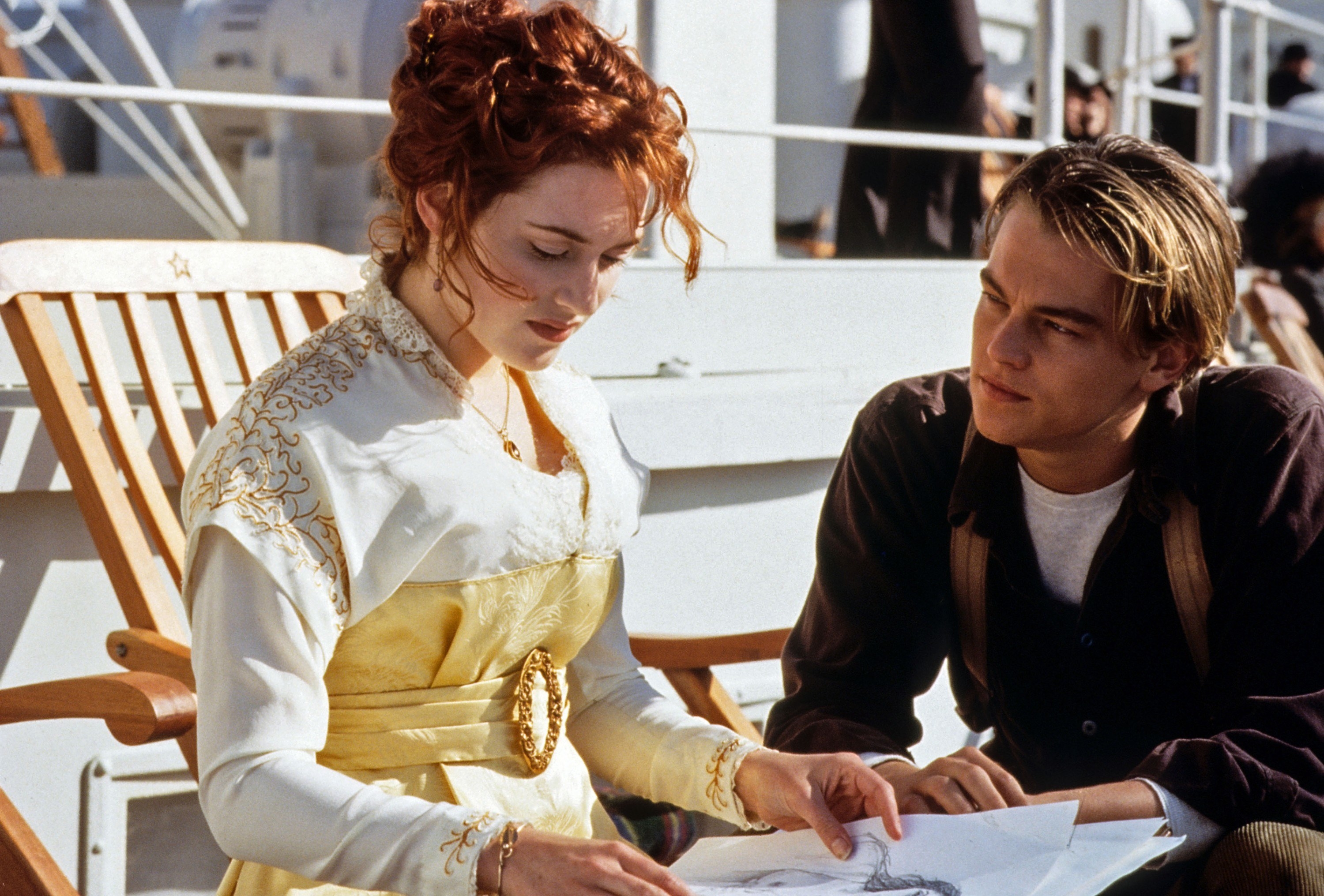 Kate Winslet shows Leonardo DiCaprio drawings while sitting down in a deck chair in the film Titanic