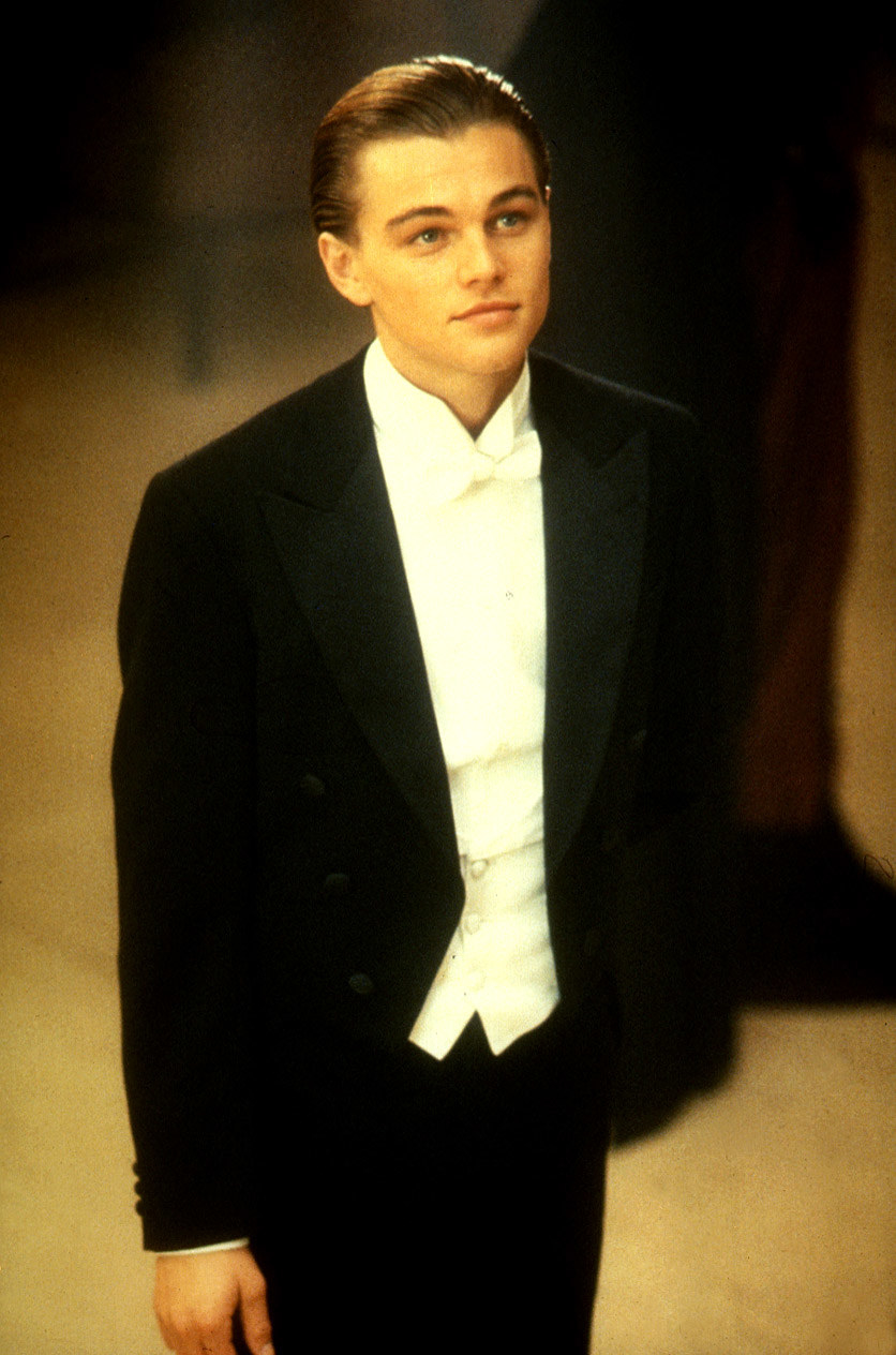 Leonardo DiCaprio stands while wearing a tuxedo in Titanic