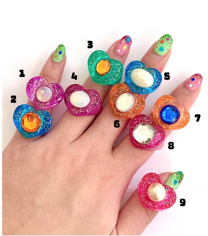hand with various colored glitter lucky gems rings