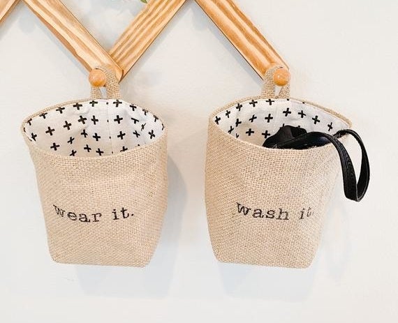 Two baskets hanging from pegs on the wall with one that says &quot;wear it&quot; and &quot;wash it&quot; 