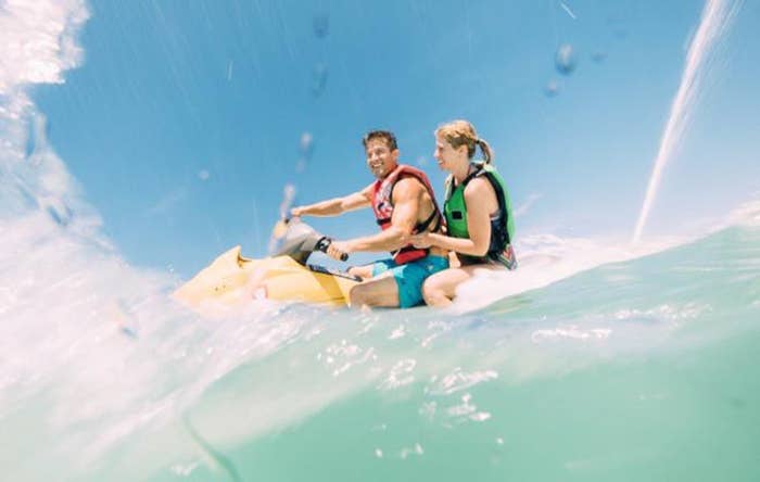 A couple driving a jet ski through a wave