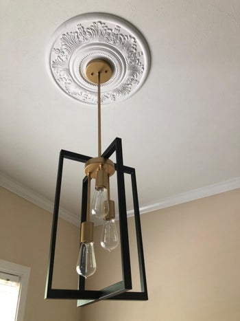 A reviewer's photo of the white medallion mounted beneath a pendant light