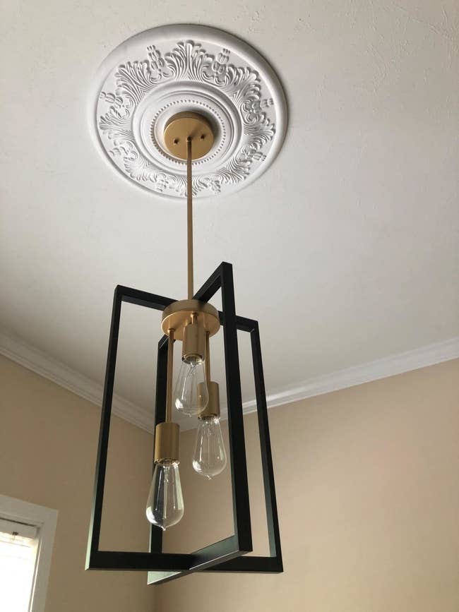 A reviewer's white medallion mounted beneath a pendant light