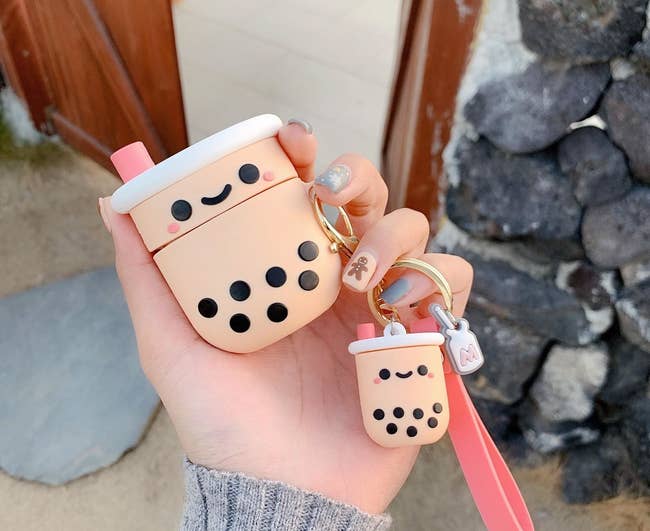 a person holding the boba airpods case and keychain