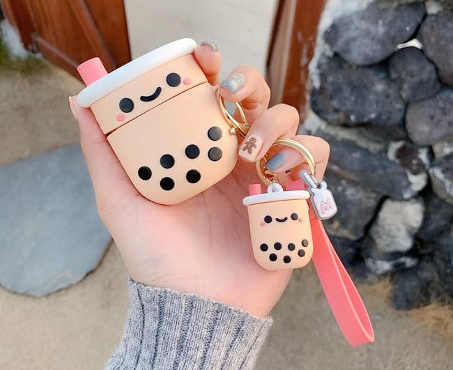 a person holding the boba airpods case and keychain
