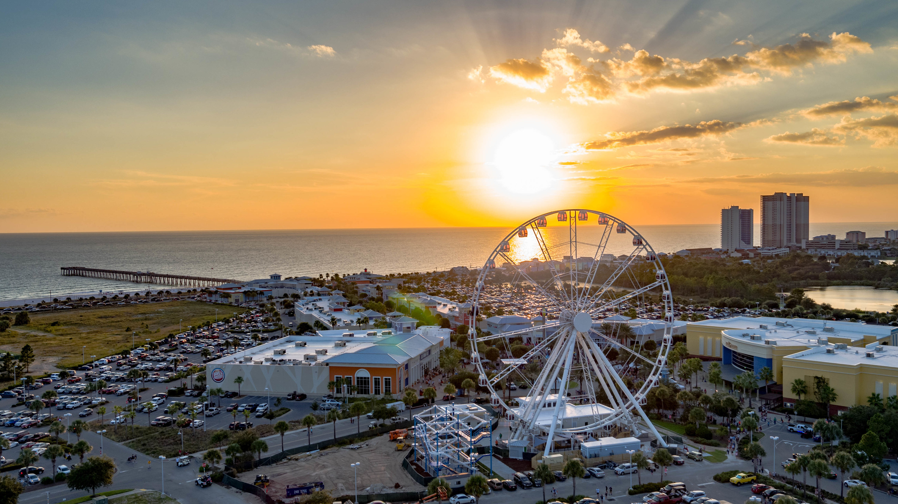 An aerial view of an amusement park at sunset featuring a ferris wheel