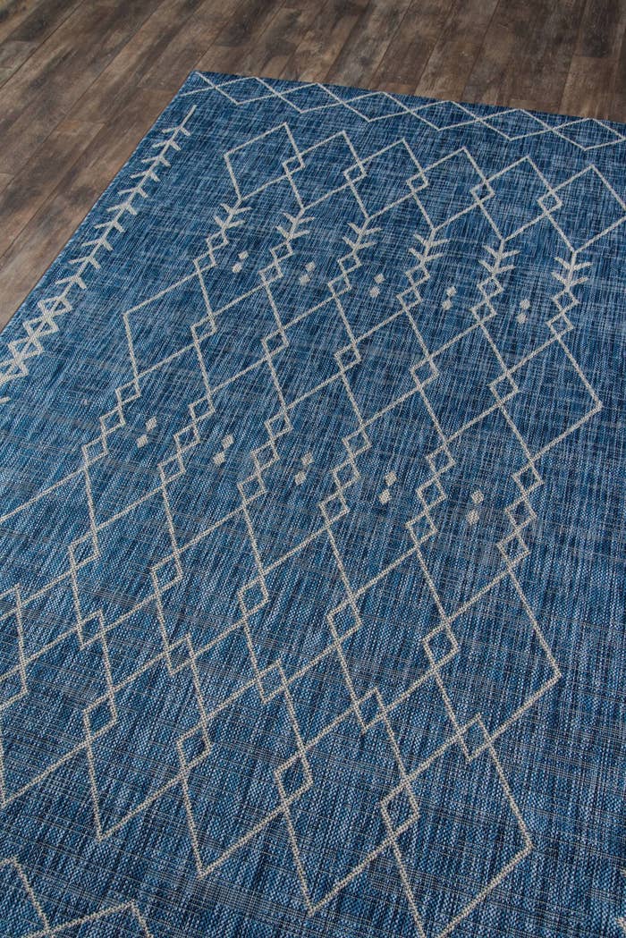 The rug in blue, which has a gray print of interlocking triangles in outline