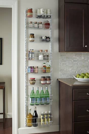 the white tiered rack mounted to the wall and filled with pantry items 