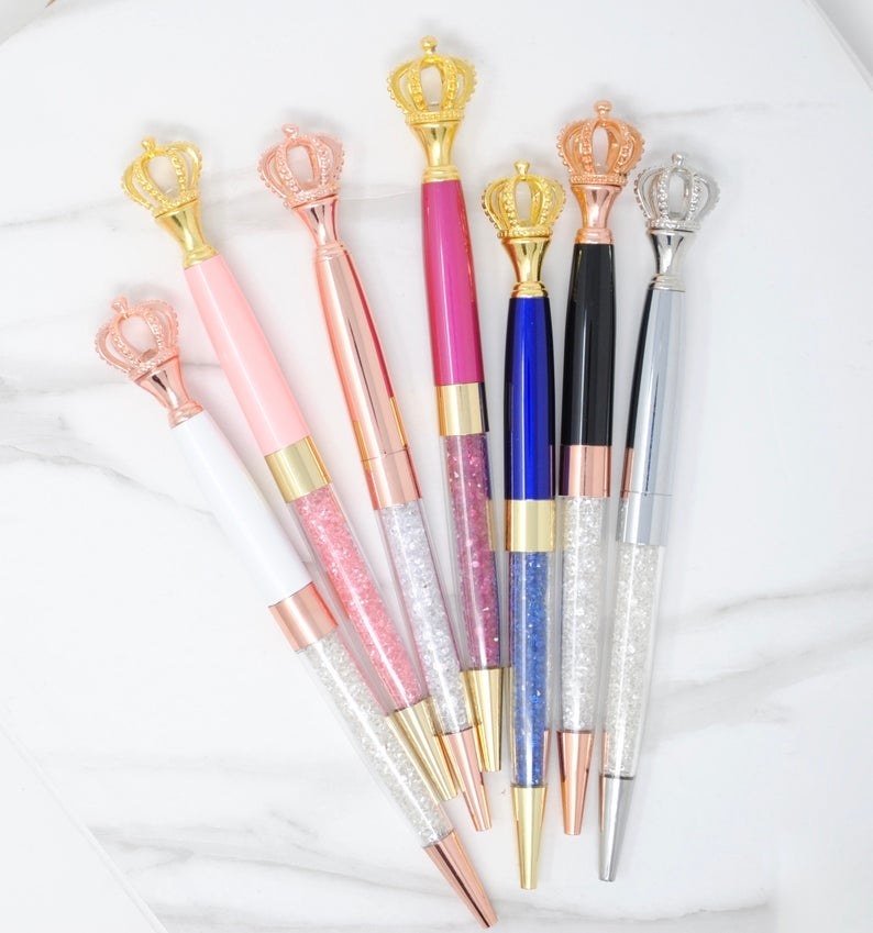 Seven pens with crown-shaped toppers with different colors