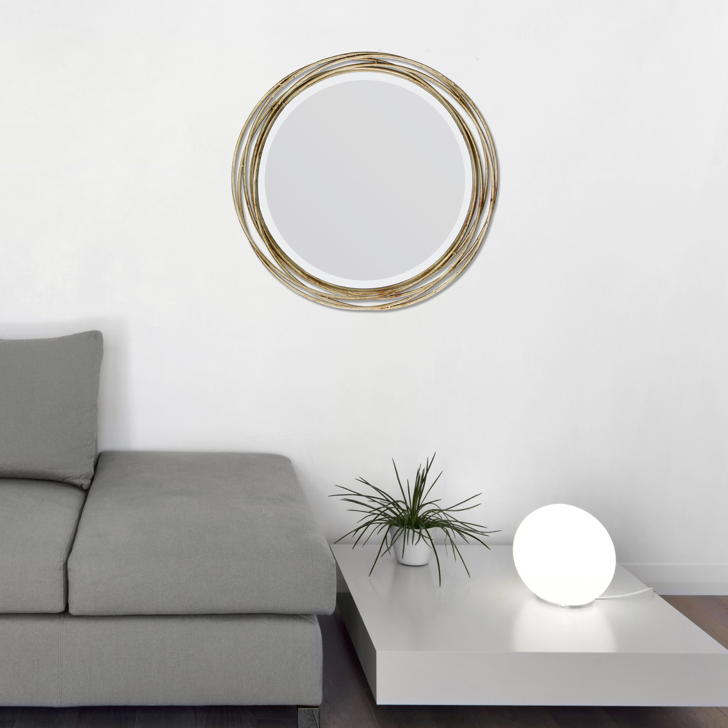 The mirror, which is round and surrounded by several loops of gold-toned wire