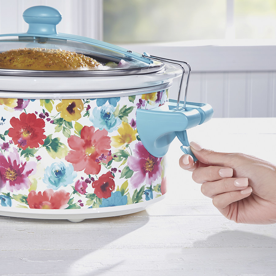 A model demonstrating the top clip on this floral and light blue slow cooker