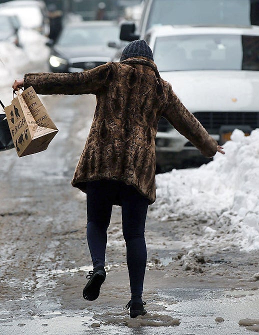 A person with their arms raised for balance as they navigate through the snow and slush