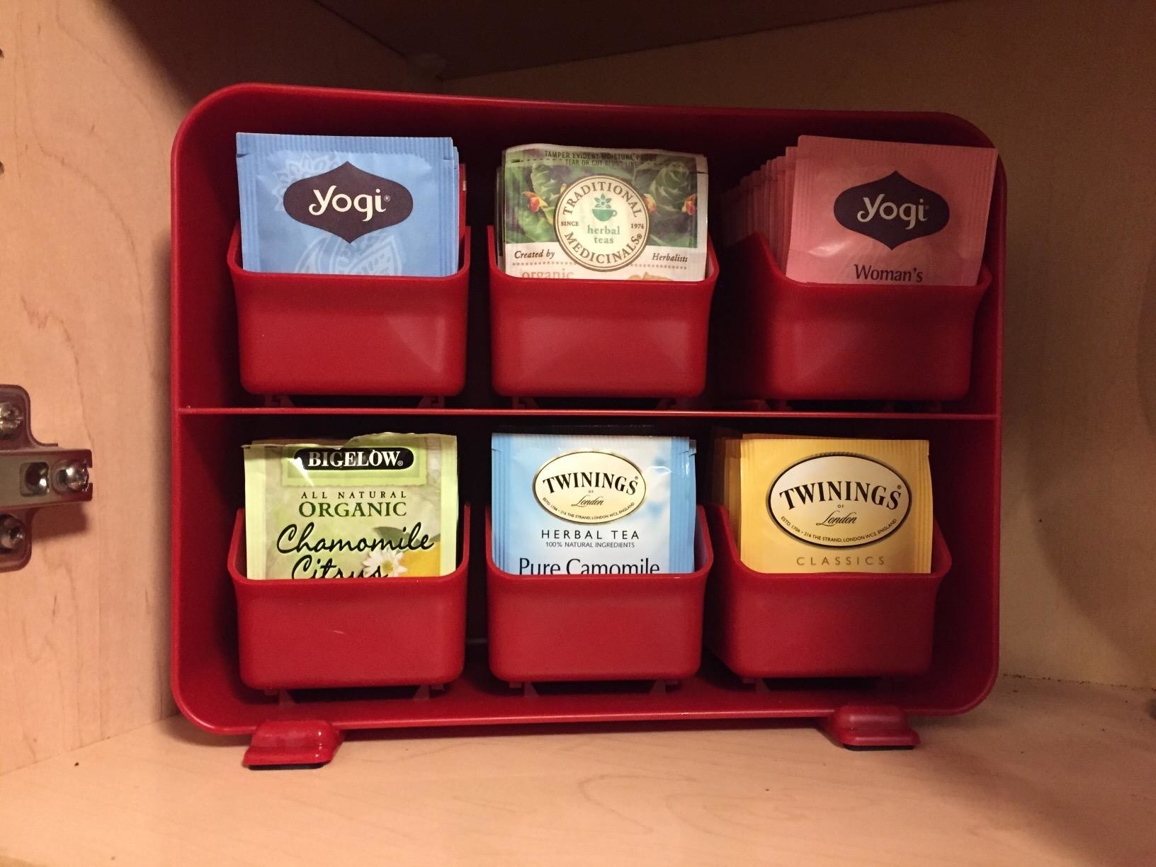 The tea bag holder in red with all six drawers filled with different indiivdually-wrapped tea bags