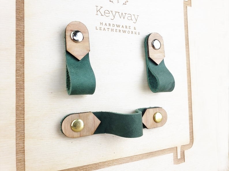 The green leather pulls which are finished with gold, silver, and wood details