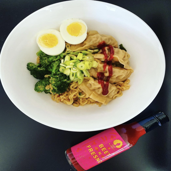 Noodle and dumplings dish drizzled with Beet N Fresno hot sauce