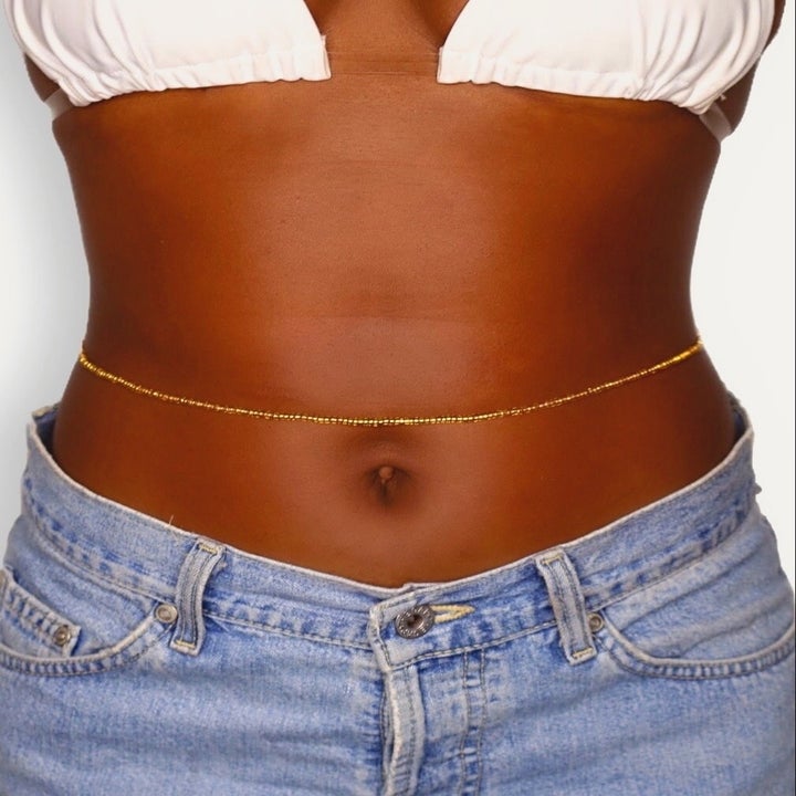 Model wearing the gold beads above their belly button