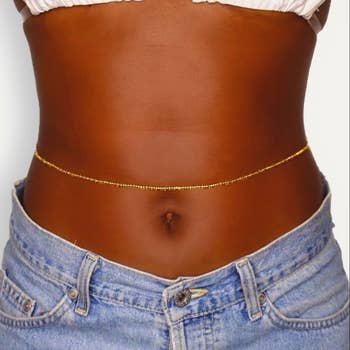 Model wearing the gold beads above their belly button