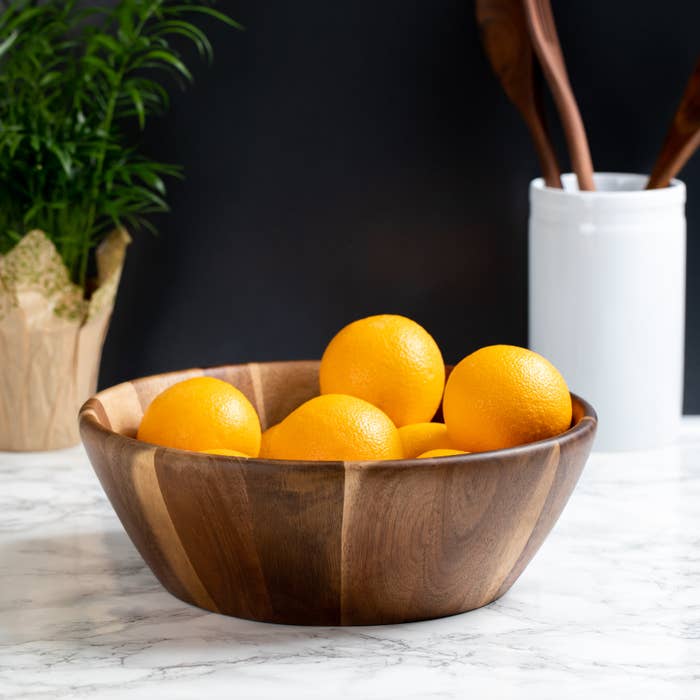 wood bowl on a table with oranges inside