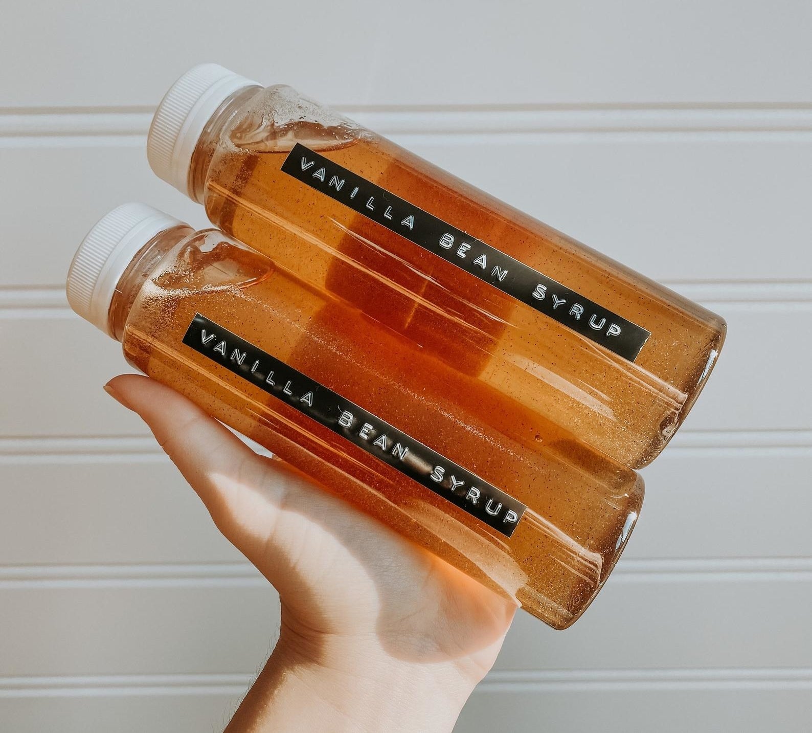 person holding two bottles of vanilla bean syrup