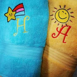two embroidered towel with a letter and a cute design