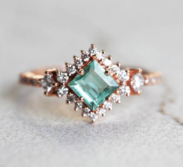 the ring with sapphire middle surrounded by smaller diamonds