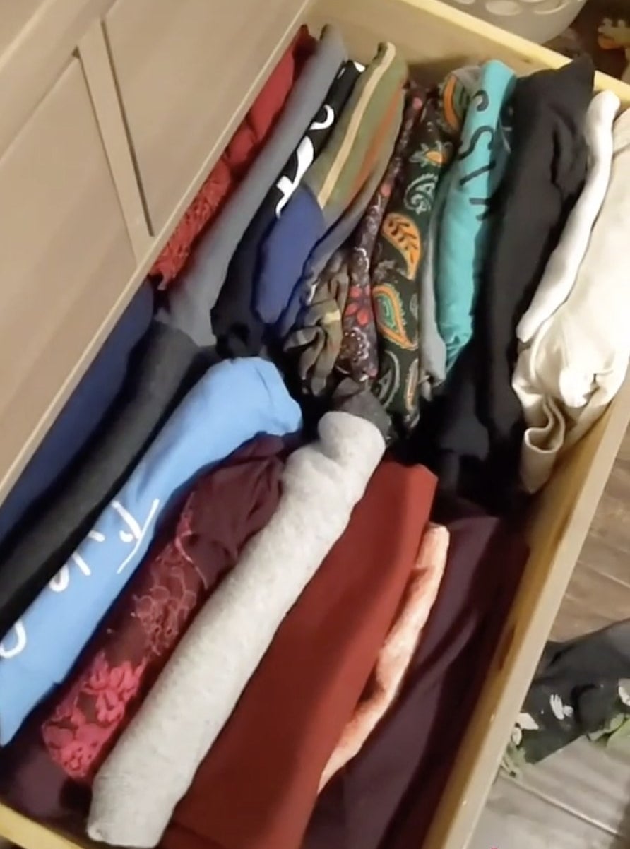 A drawer filled with shirts folded facing up so the owner can see all her shirts at once