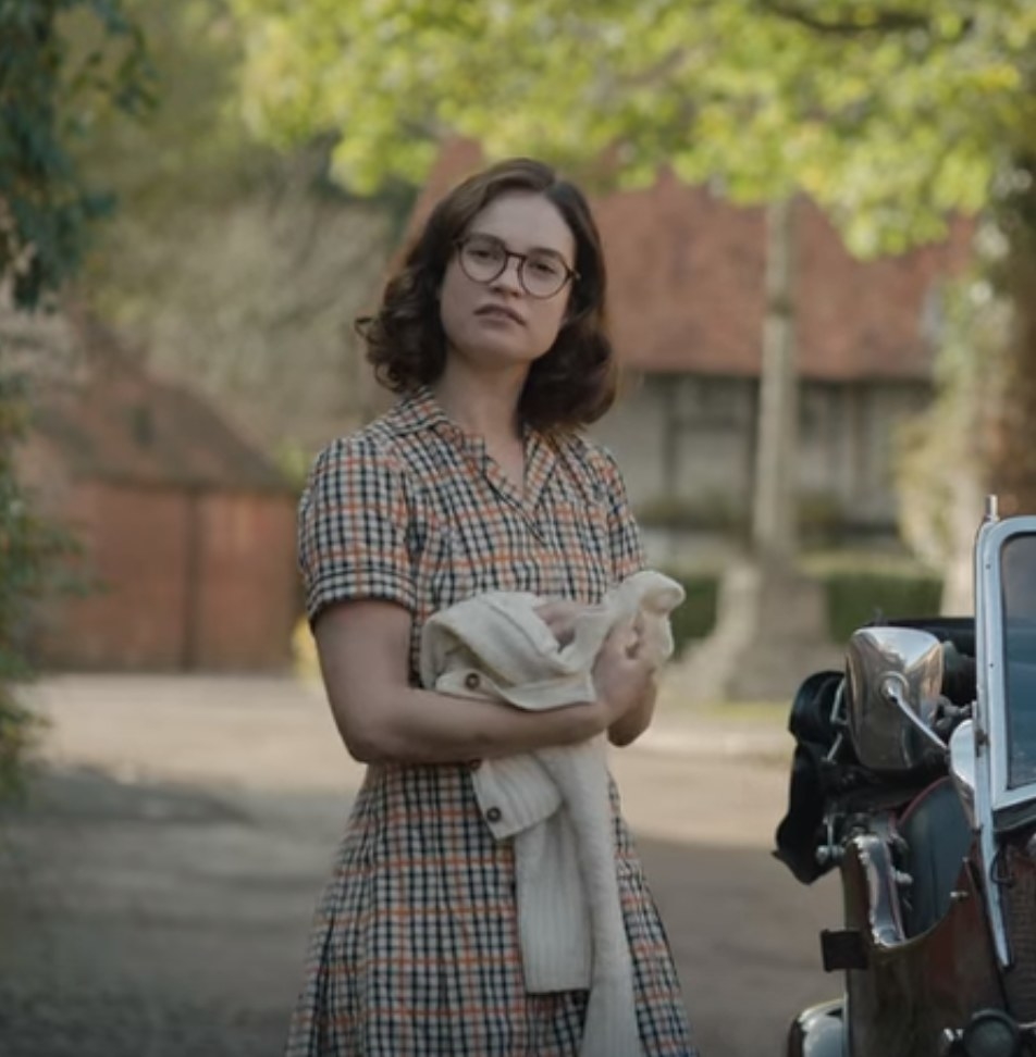 Still from The Dig: Peggy holding cardigan in plaid dress