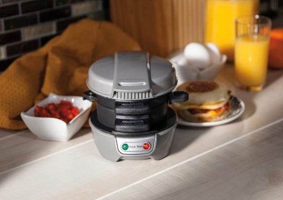 The sandwich maker shown on a kitchen counter with breakfast foods