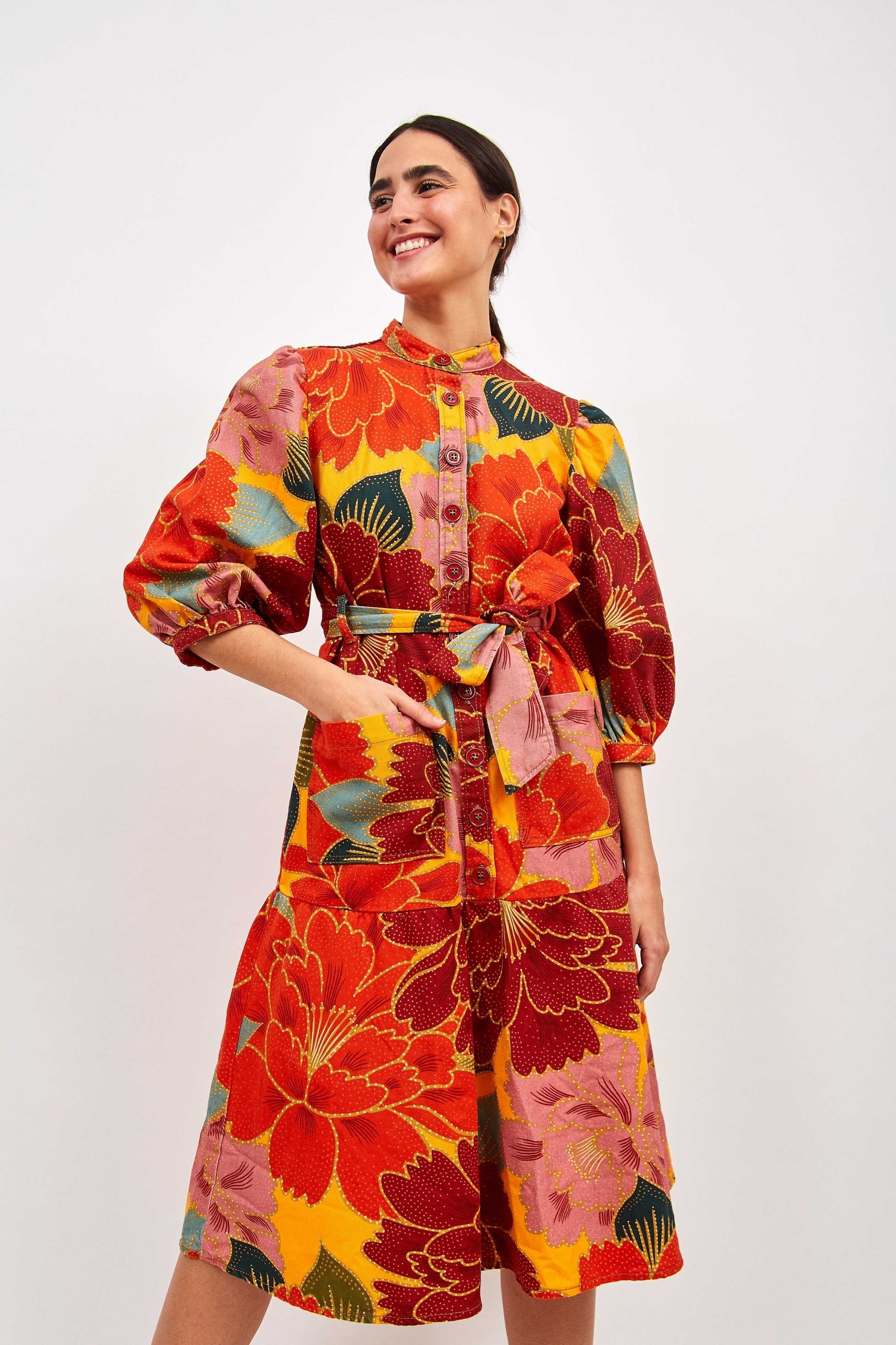model wearing a super colorful floral dress with button up detailing and a tie waist