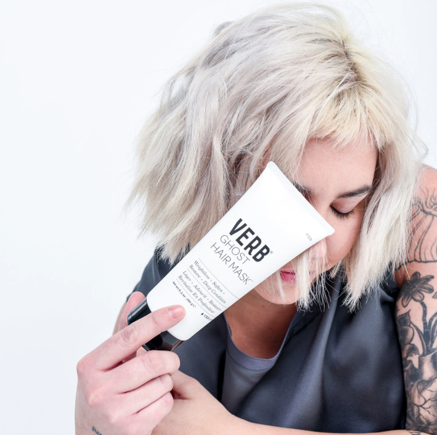 model with bleached hair holding tube of hair mask