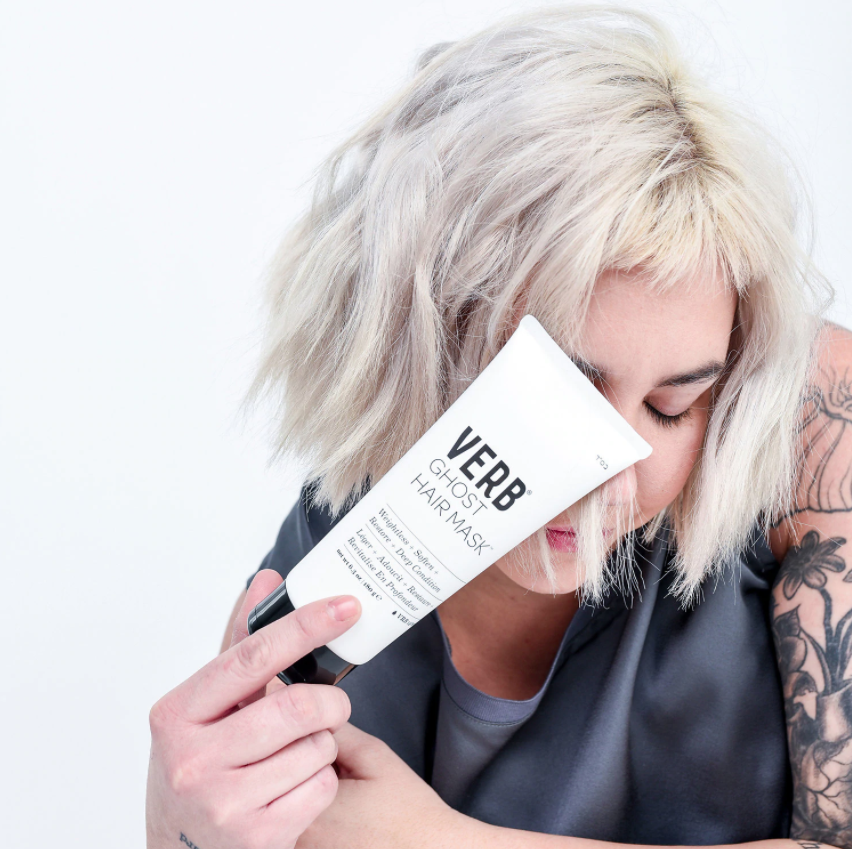 model with bleached hair holding tube of hair mask 