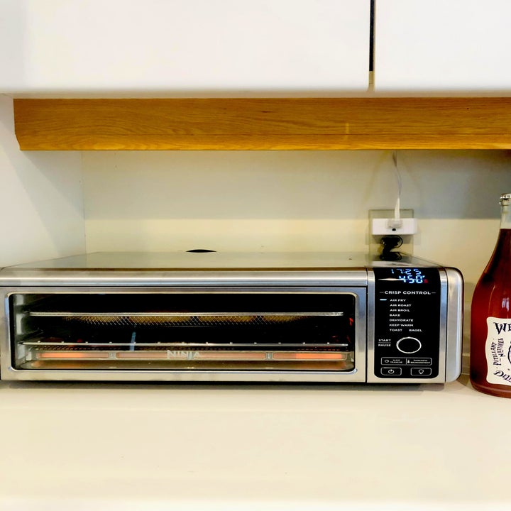 The oven with a bottle of wine beside it
