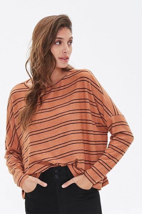 Model wears orange and black striped top with black jeans